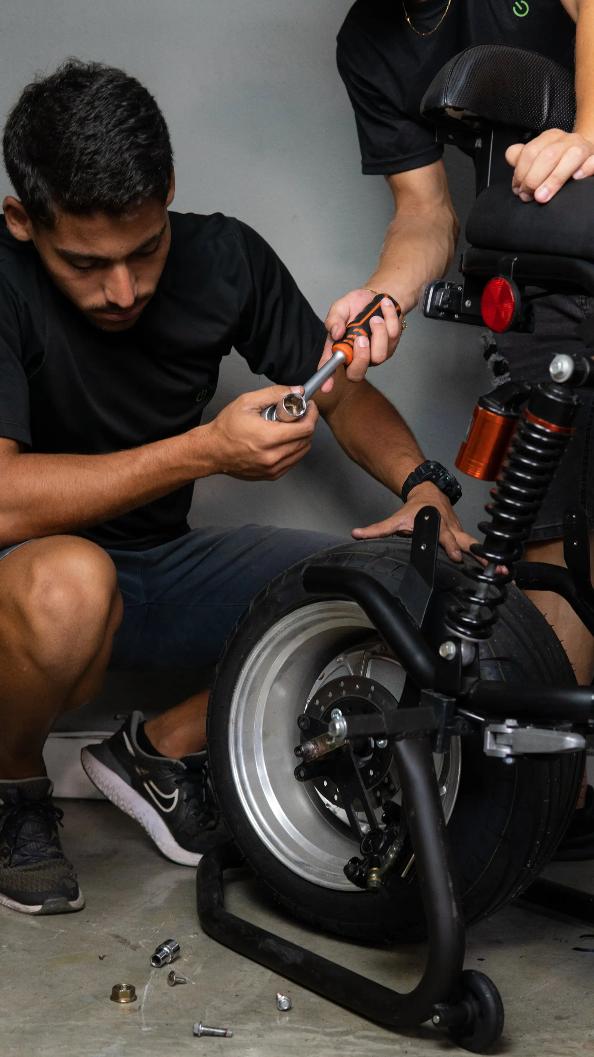 Técnicos C-MOBI em manutenção na roda de uma scooter elétrica